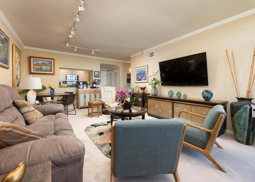 Open living and dining space with views into kitchen. Sofa, two chairs, tv and dining table fit comfortably.